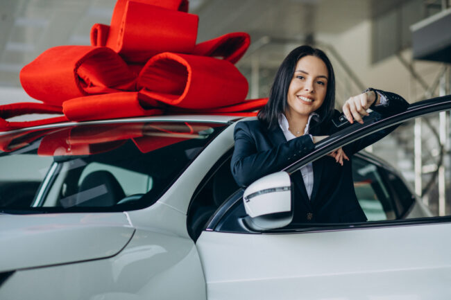 Woman by the car with big red bow